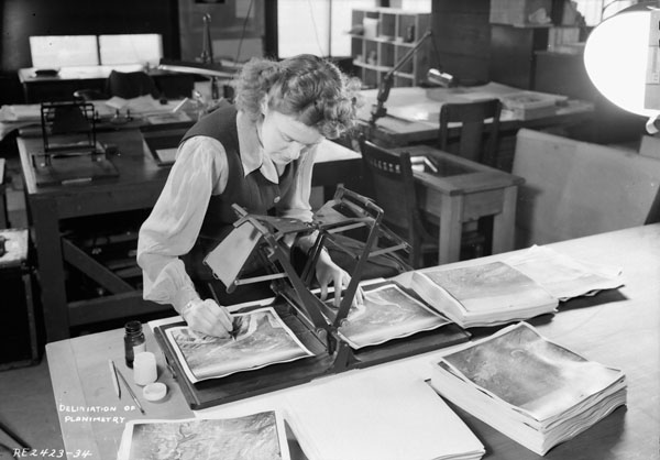 A woman is seen annotating an overlapping air photo pair with a stereoscope in 1945. Canada. Dept. of National Defence / Library and Archives Canada / PA-065599, Public Domain.